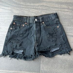 Black high-waisted Levi’s denim shorts with rips and frayed hem